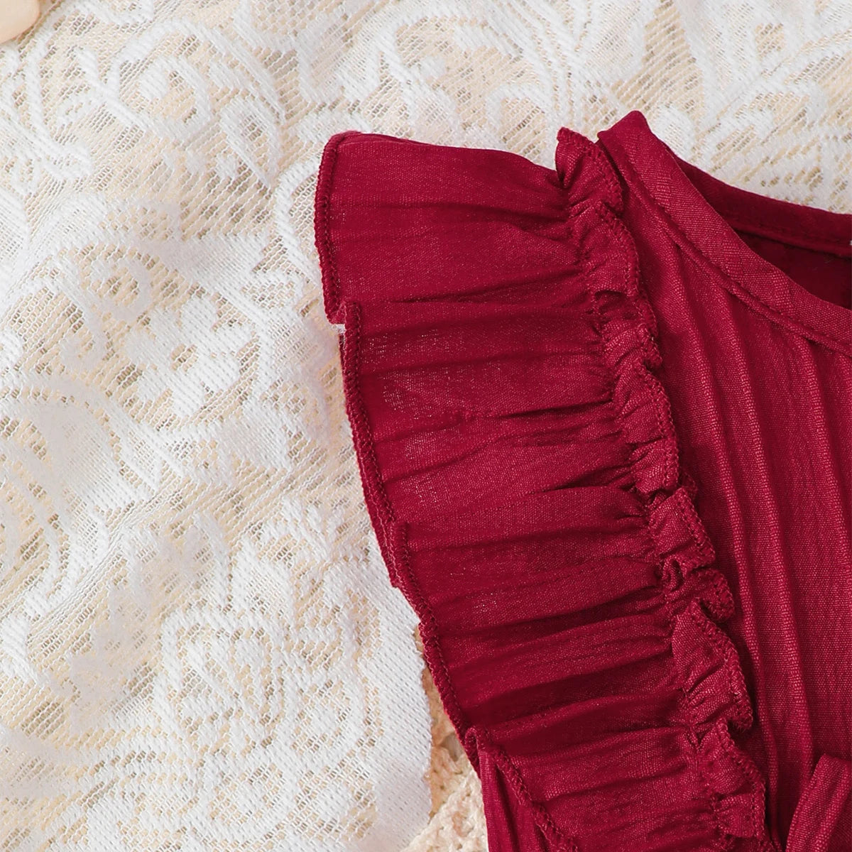 Baby girl wearing a solid colour sleeveless dress with ruffled edges and a headband