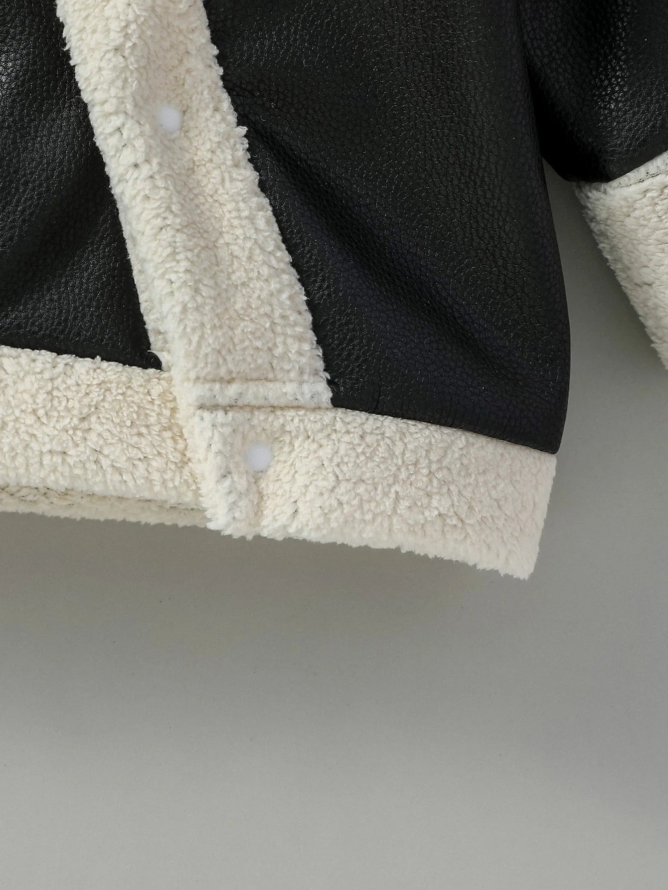 Close-up material detail of baby boys black leather winter jacket