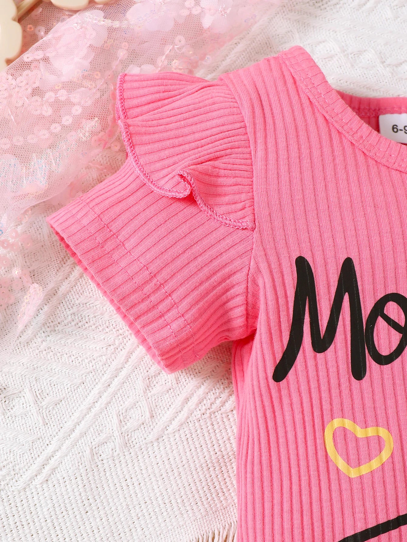 Detail view showing the fabric finish and pattern of the baby girls letter print romper and denim skirt set