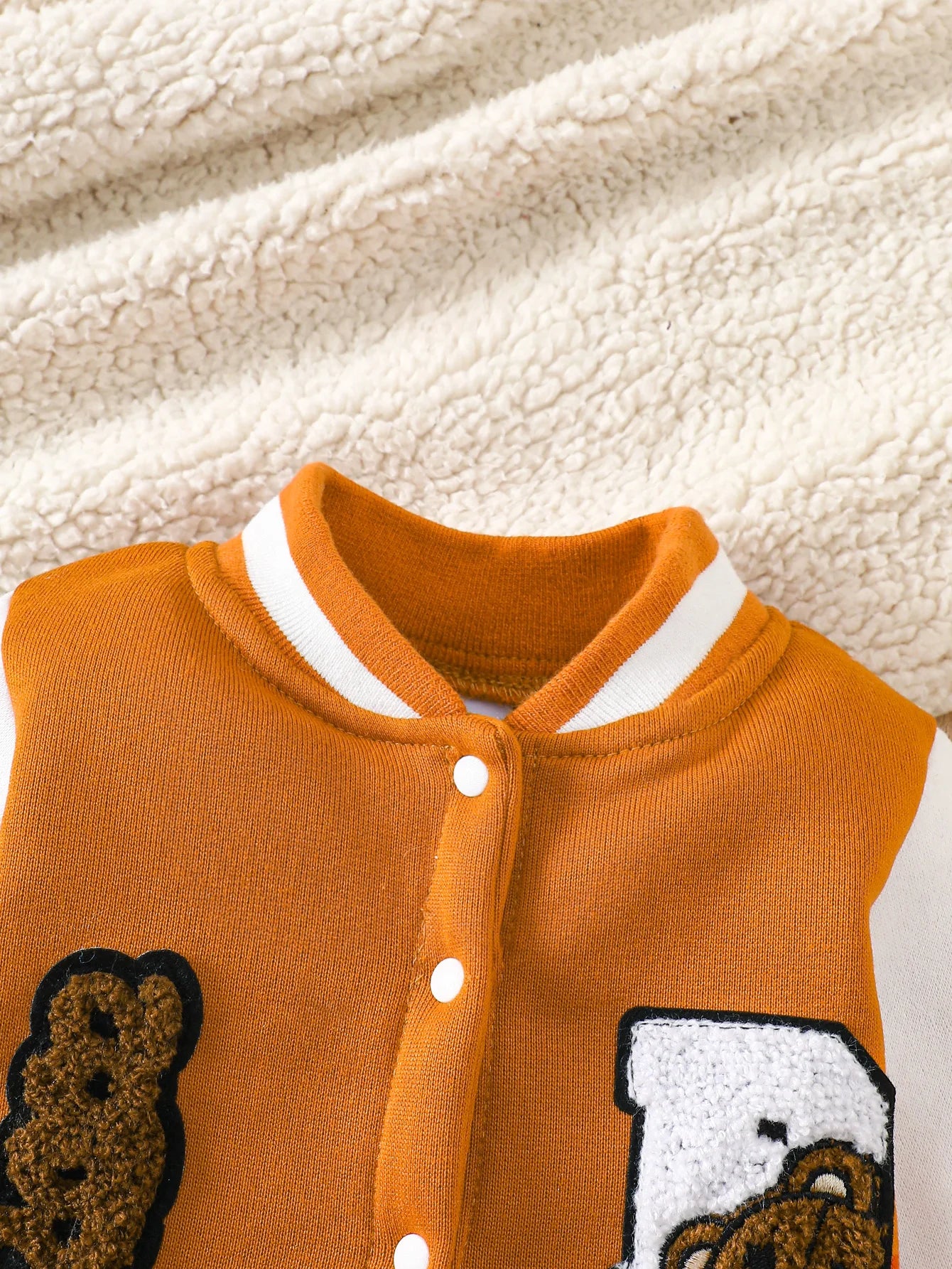 Baby boy wearing a caramel and orange fleece-lined baseball style romper