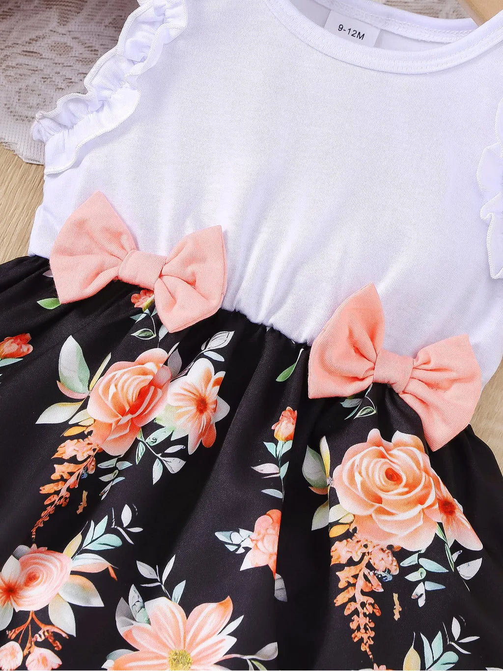 Baby girl wearing a sleeveless floral party dress with a bow