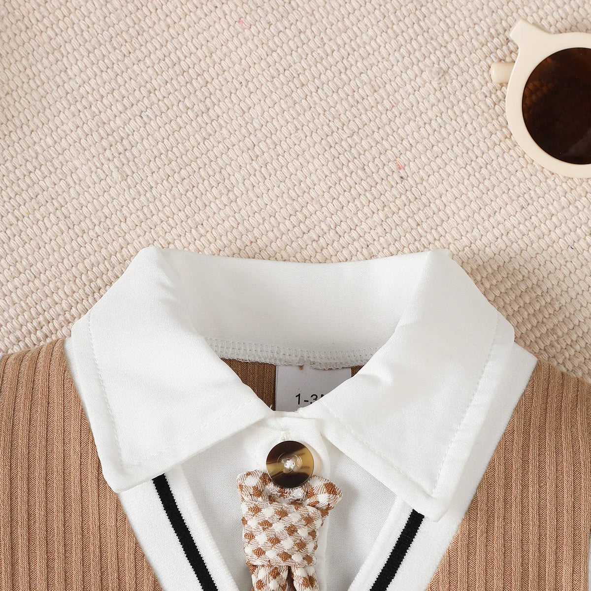 Baby boy wearing a smart short-sleeve romper with an attached tie