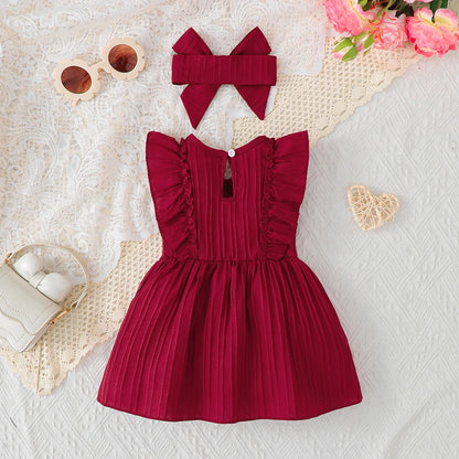 Baby girl wearing a solid colour sleeveless dress with ruffled edges and a headband