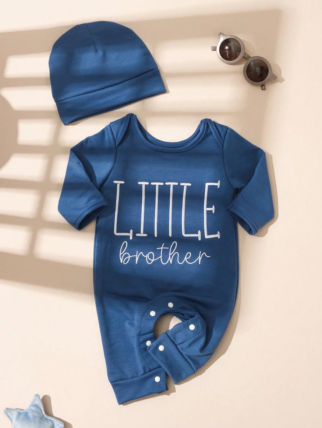 Detail shot of the Blue newborn boys letter print button bodysuit and hat