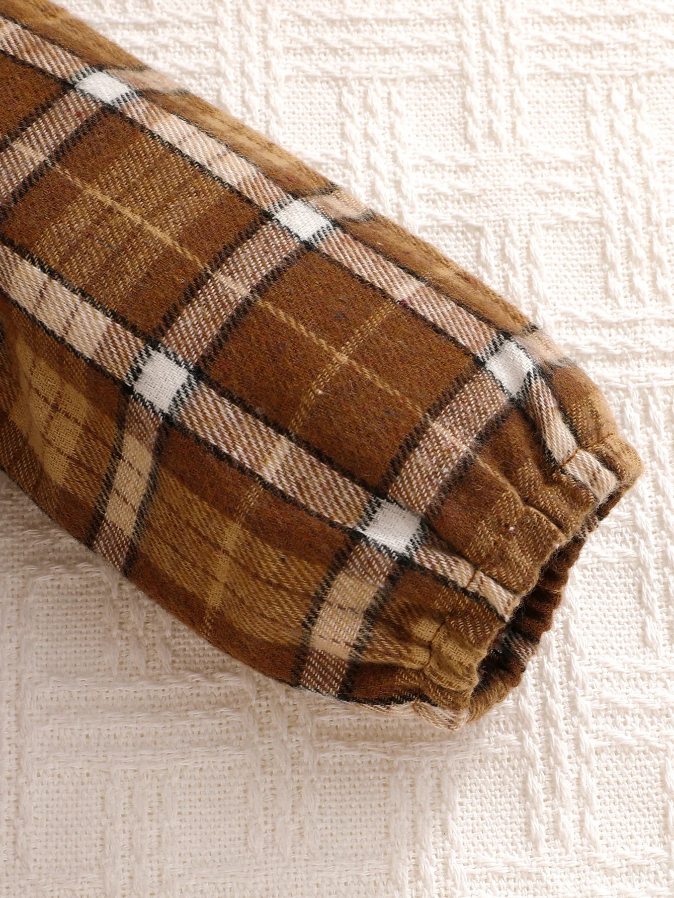 Fabric and texture detail of baby boys plaid jumpsuit with bow tie & beret