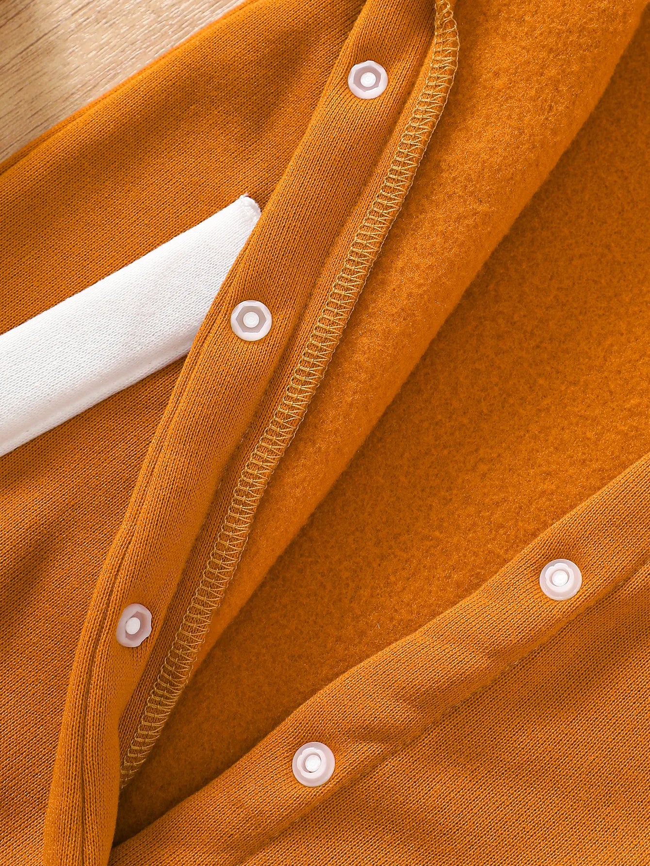 Baby boy wearing a caramel and orange fleece-lined baseball style romper