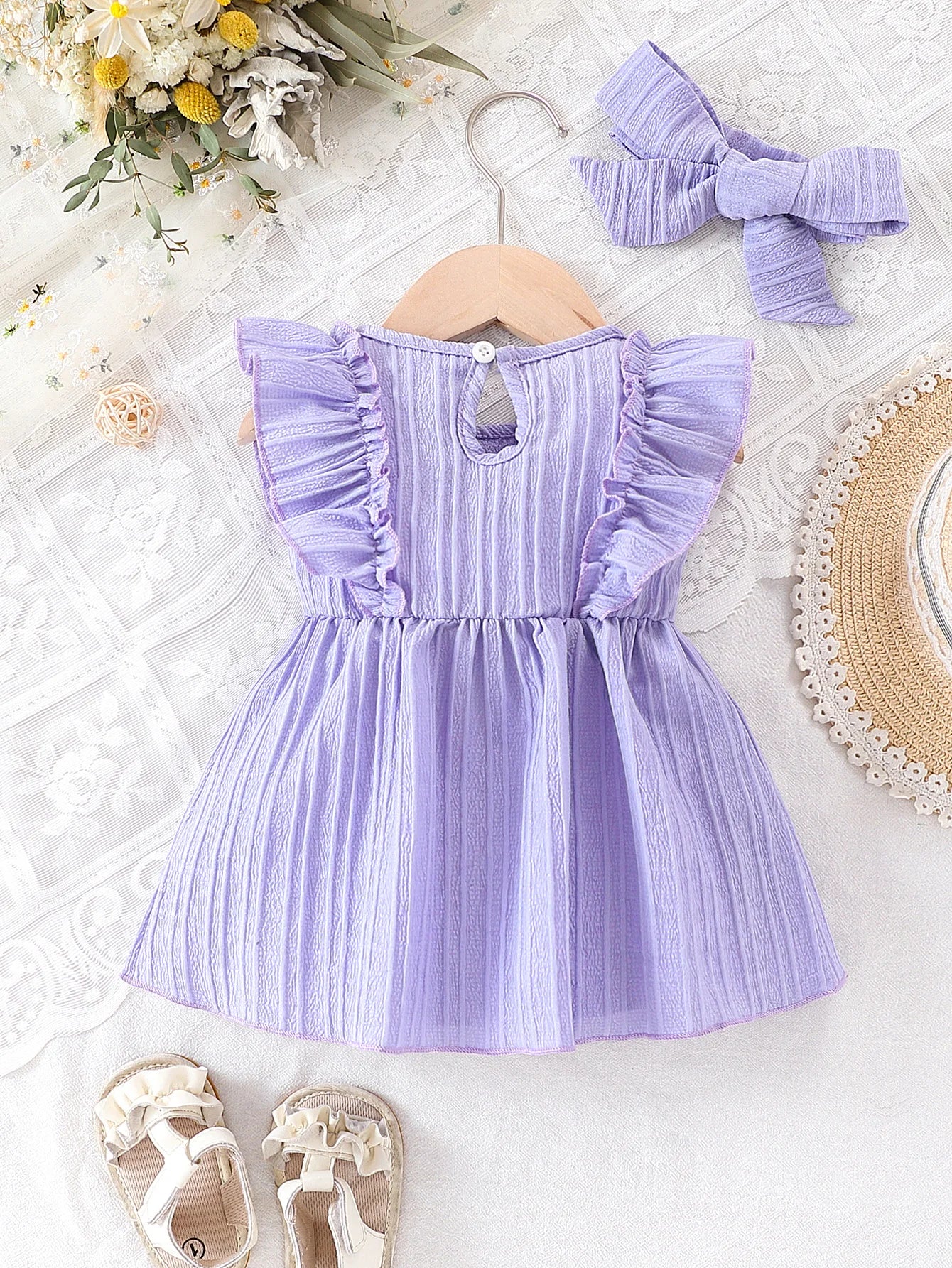 Baby girl wearing a purple ruffle dress with a bow and matching headband