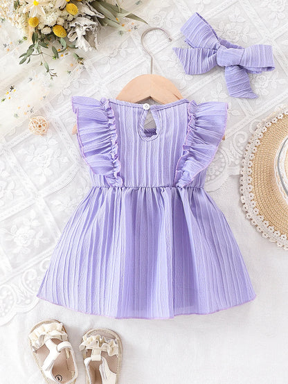 Baby girl wearing a purple ruffle dress with a bow and matching headband