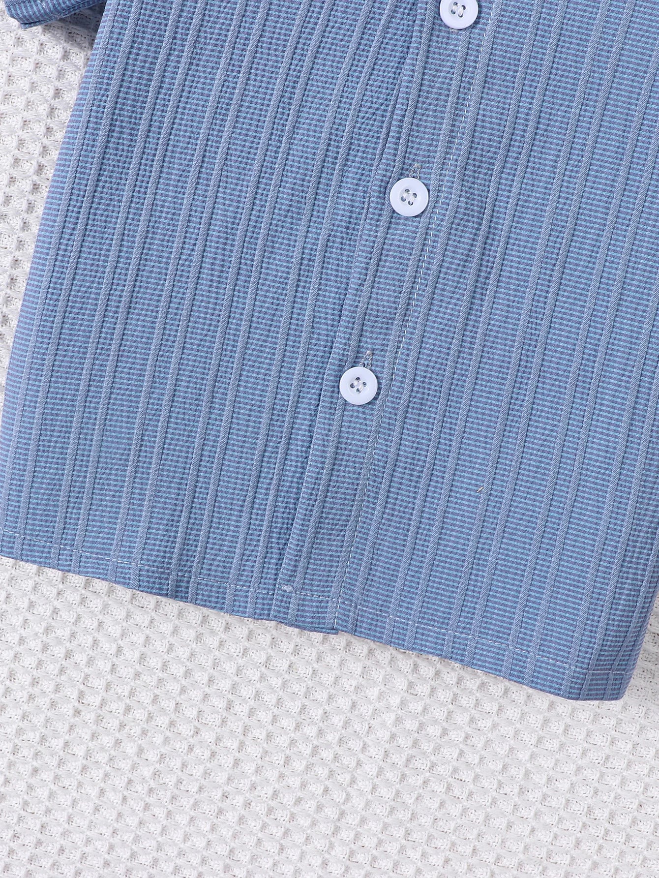 Close up highlighting the hem and stitching on the baby boys woven jacquard shirt and shorts set