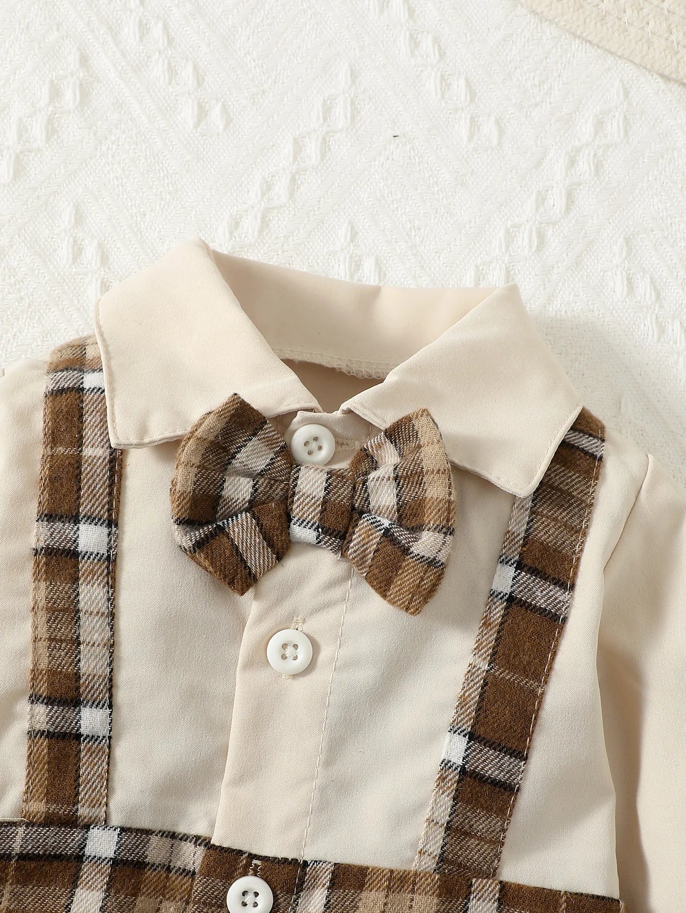 Close up highlighting the hem and stitching on the baby boys gentleman jumpsuit with suspenders and hat