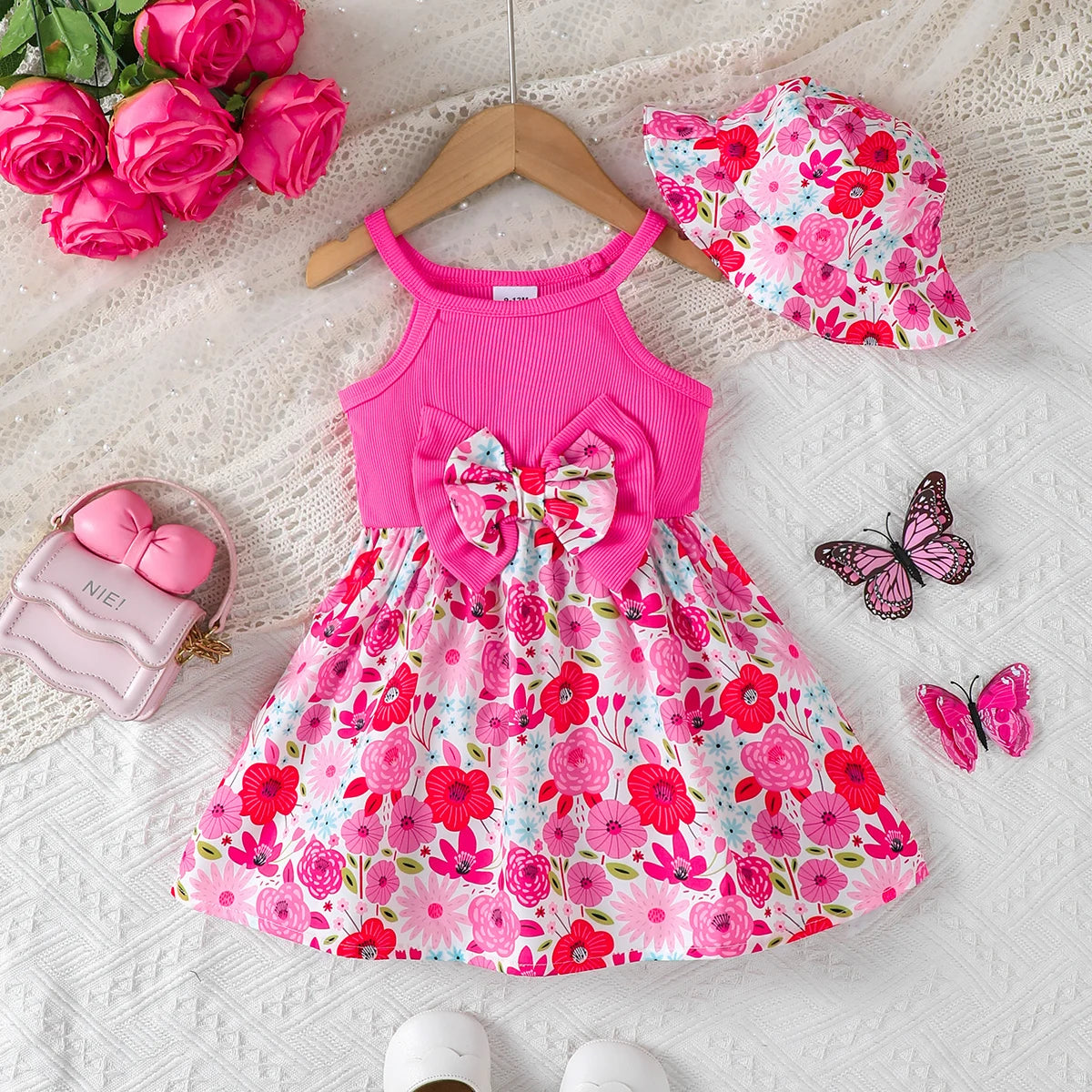 Baby girl wearing a sleeveless floral dress with a bow and matching sun hat