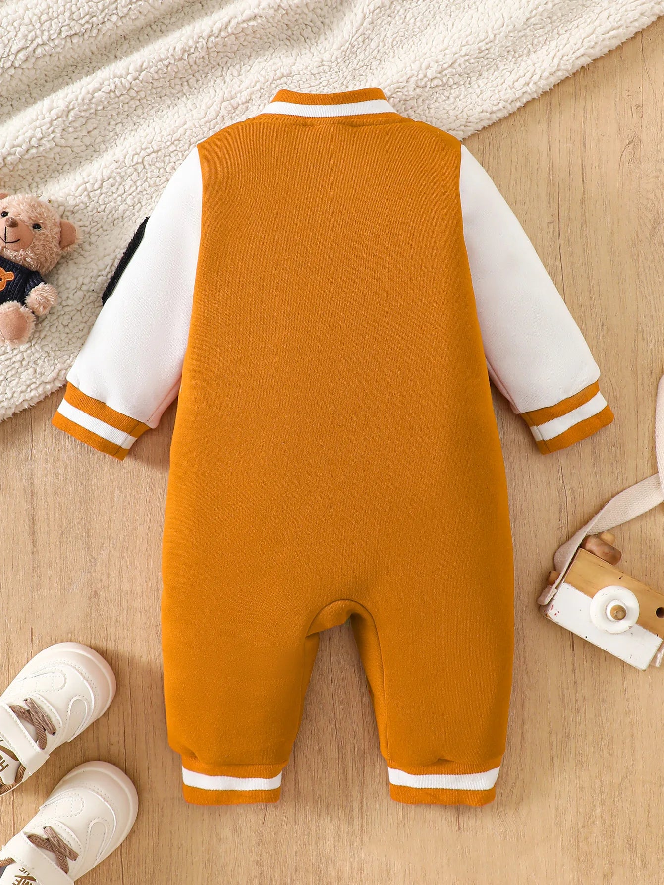 Baby boy wearing a caramel and orange fleece-lined baseball style romper