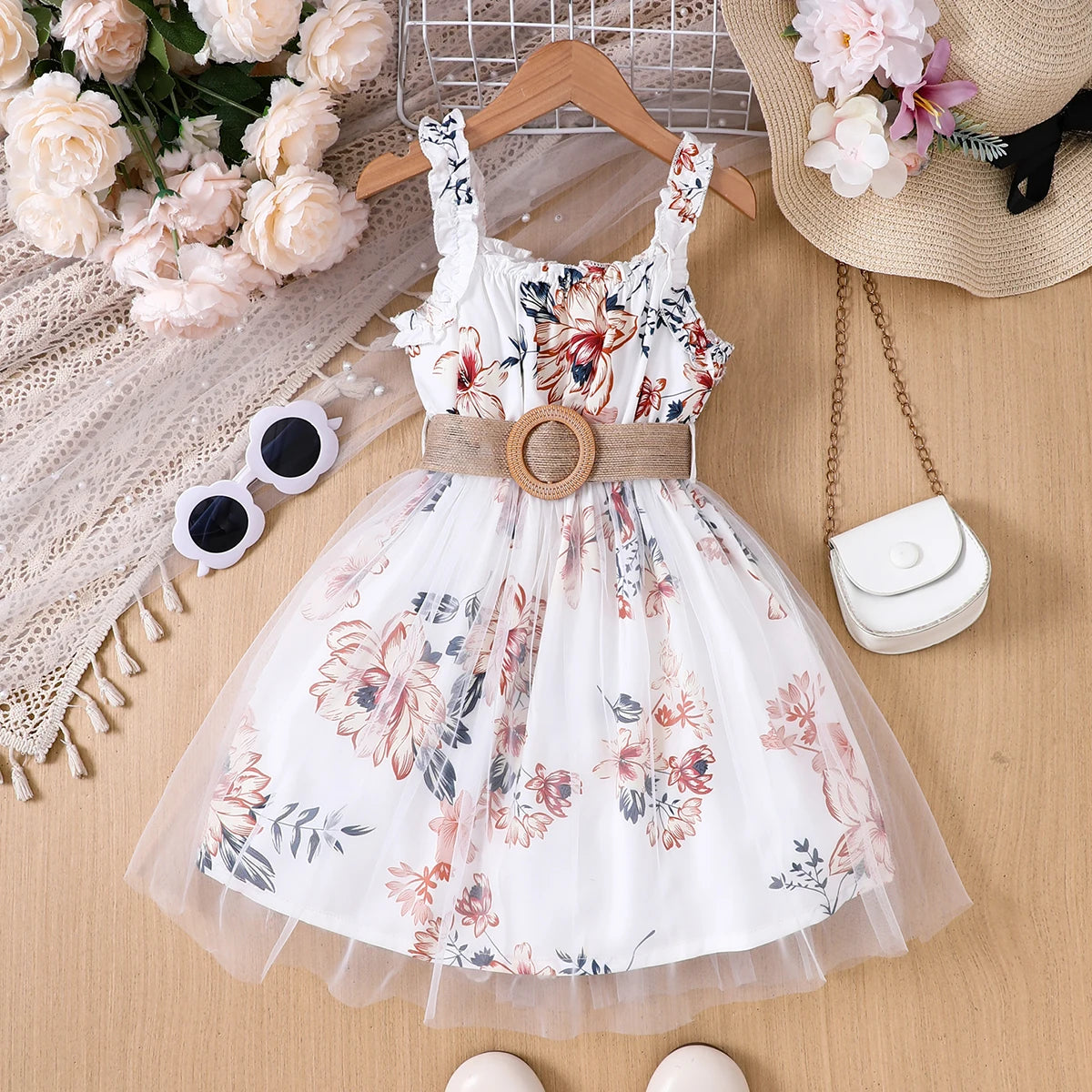 Girl wearing a floral print mesh pinafore dress with a waist belt