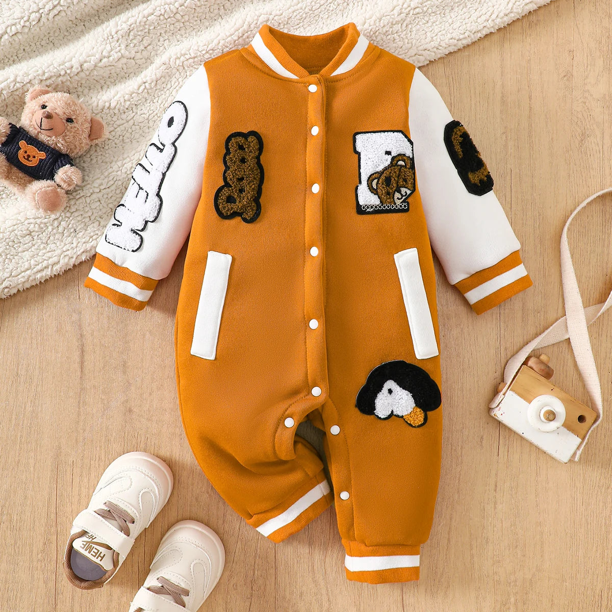 Baby boy wearing a caramel and orange fleece-lined baseball style romper