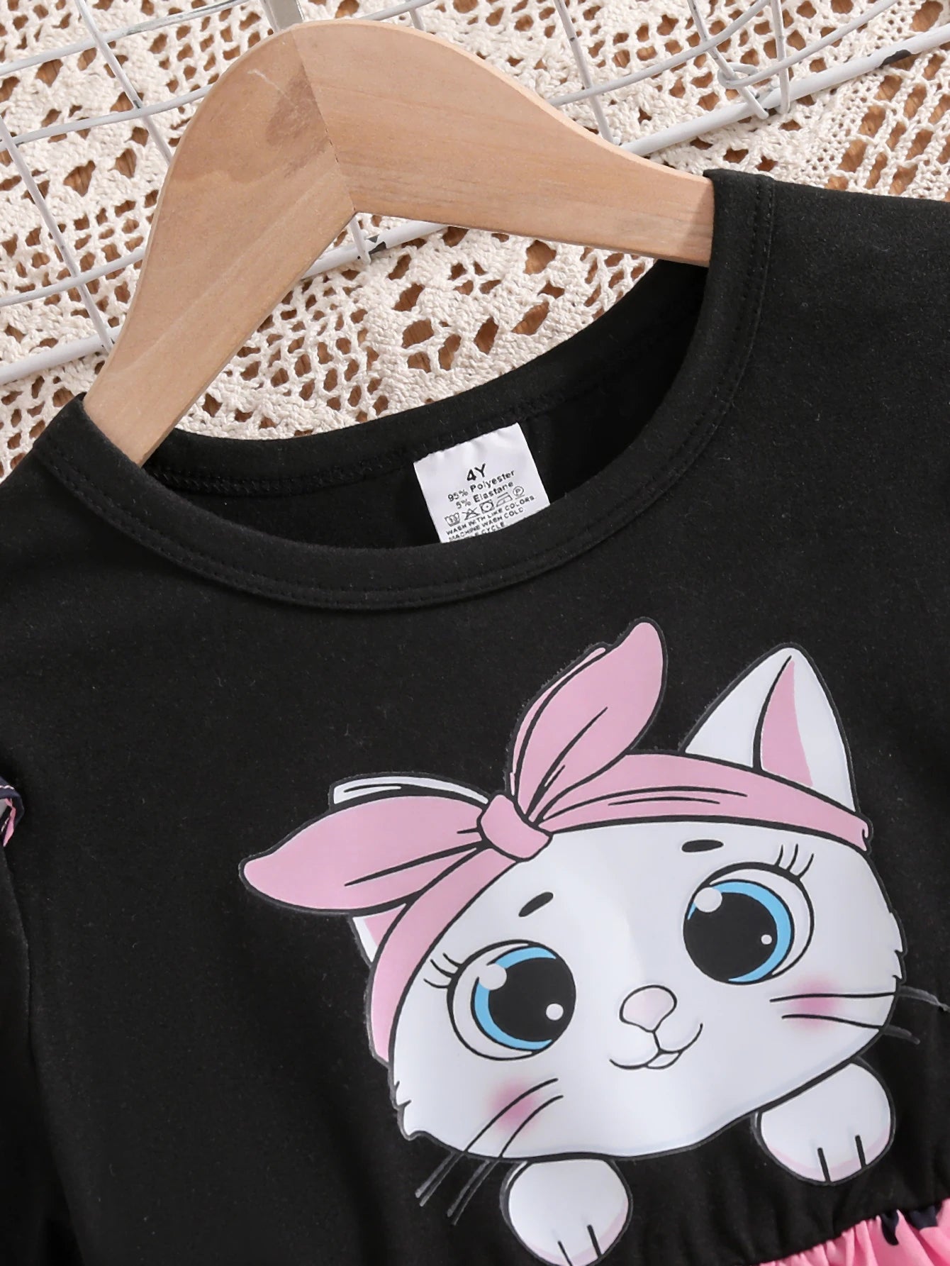 Girl wearing a mid-length dress with a cat and heart print and flutter sleeves