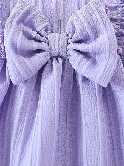 Baby girl wearing a purple ruffle dress with a bow and matching headband