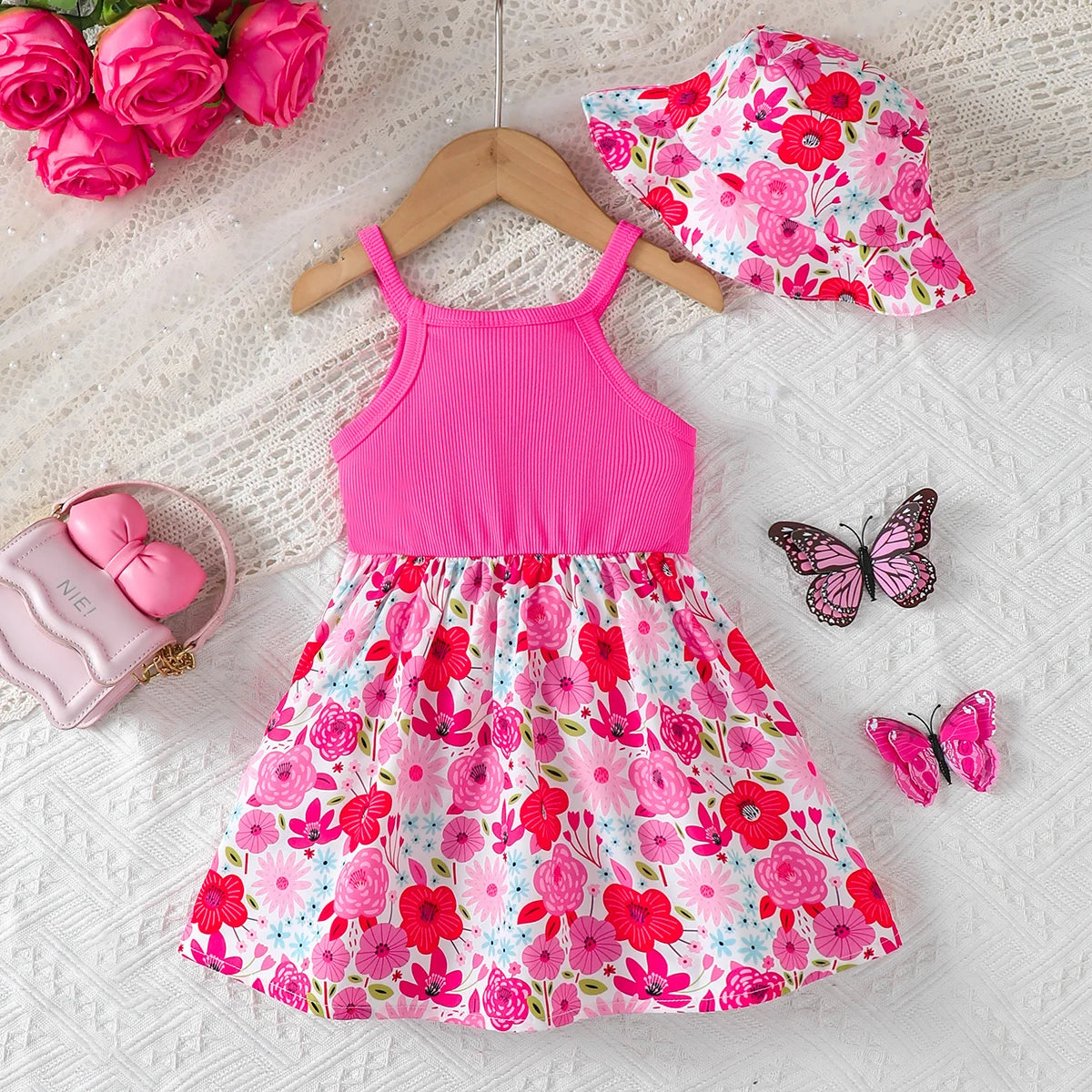 Baby girl wearing a sleeveless floral dress with a bow and matching sun hat
