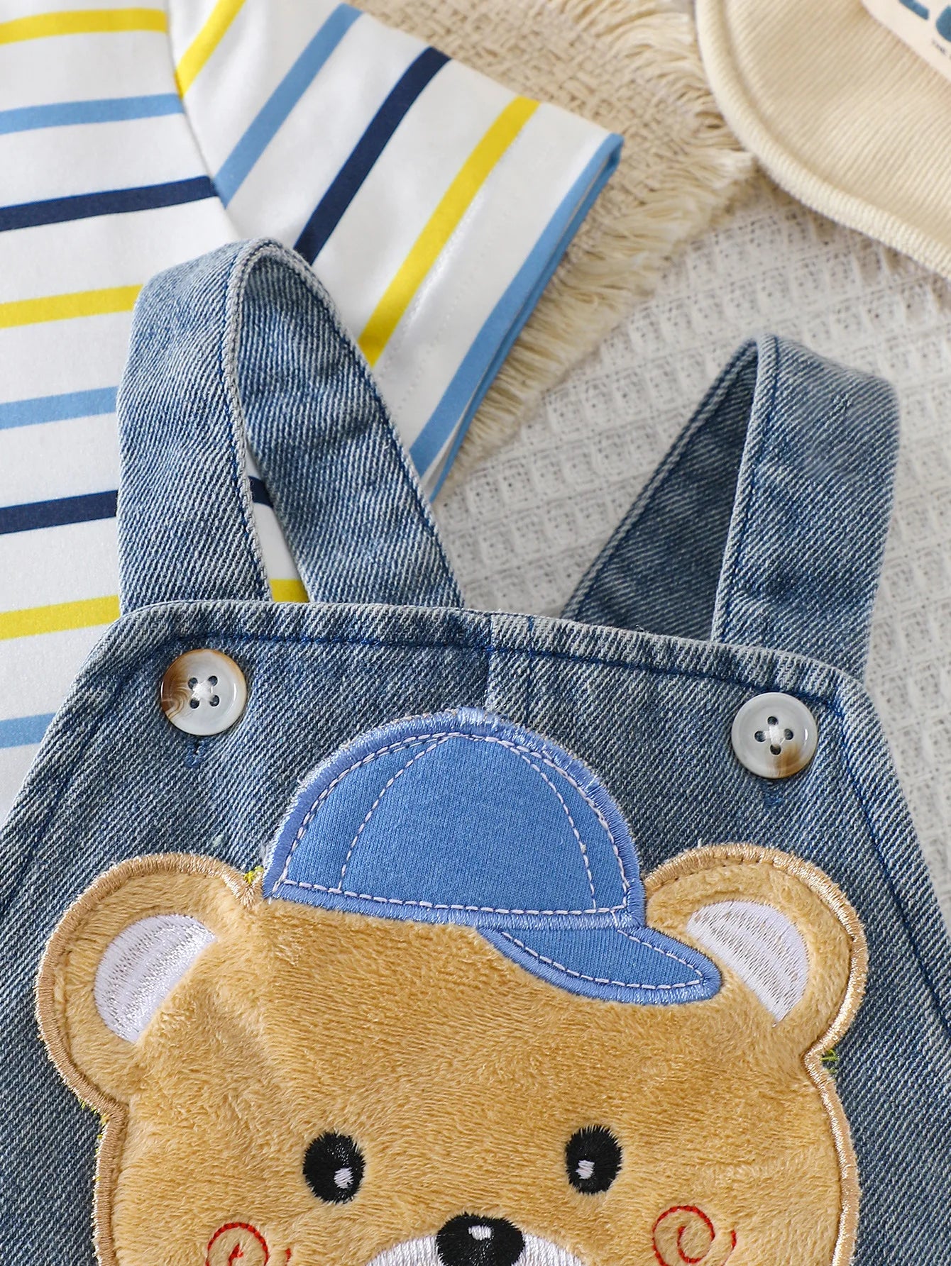 Close-up material detail of baby boys striped t-shirt and bear denim overalls set