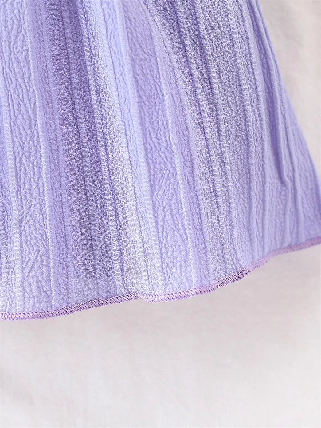 Baby girl wearing a purple ruffle dress with a bow and matching headband