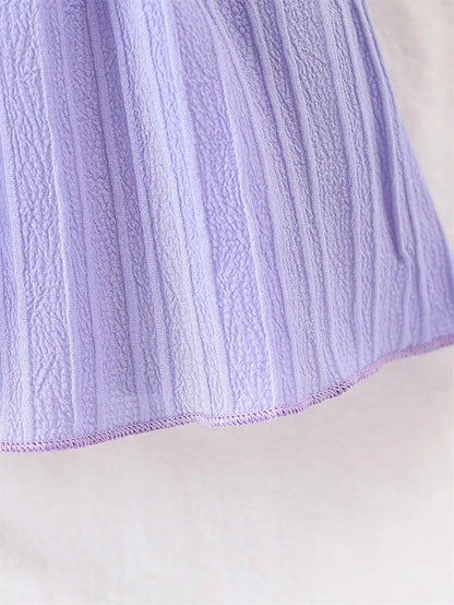 Baby girl wearing a purple ruffle dress with a bow and matching headband