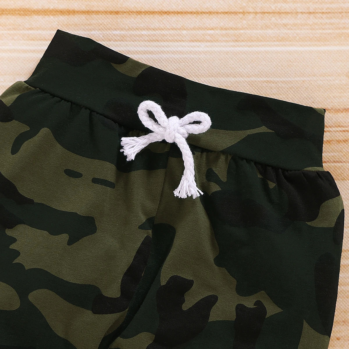 Close up highlighting the hem and stitching on the baby boys camouflage shorts and letter print romper set