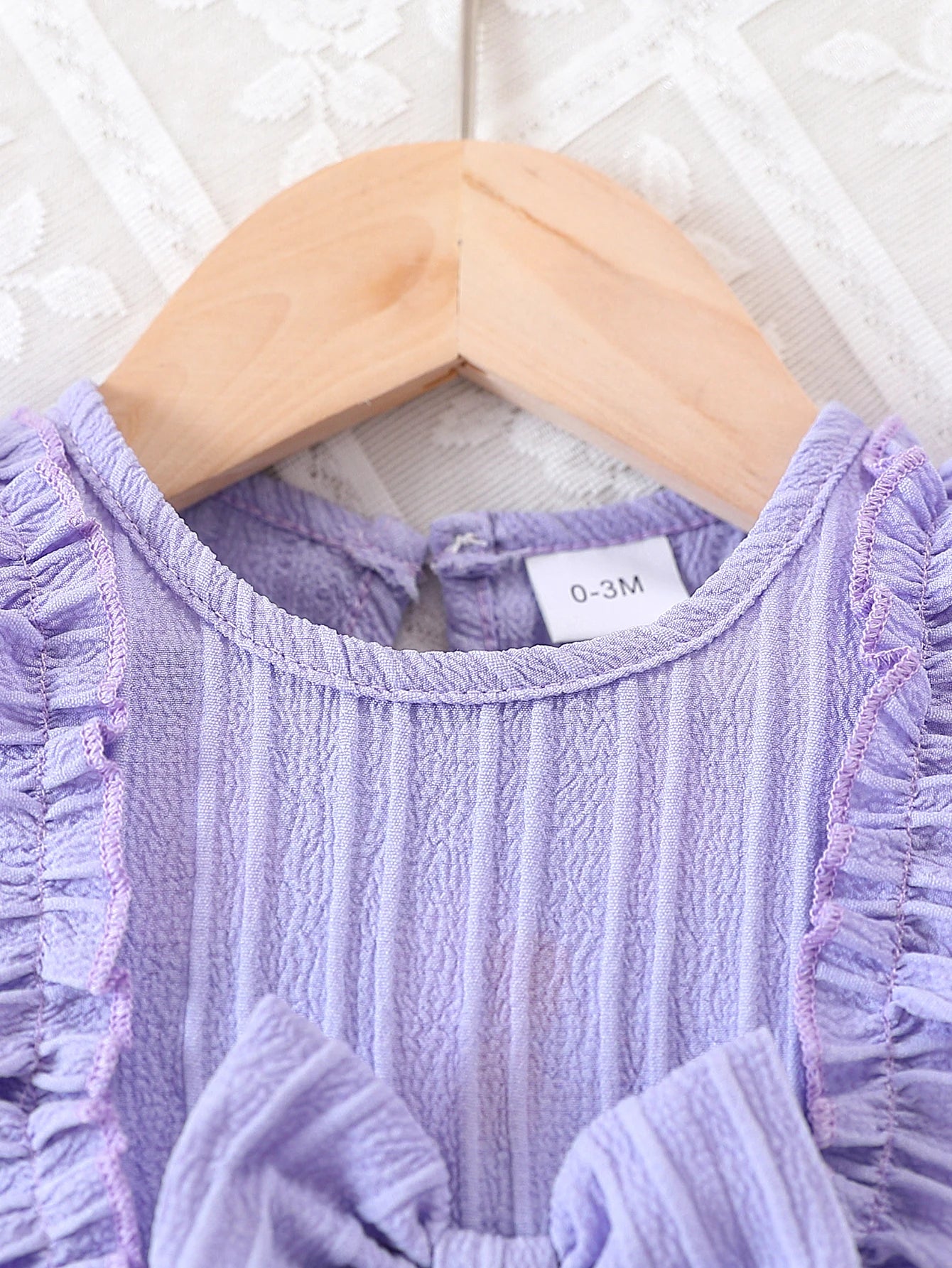 Baby girl wearing a purple ruffle dress with a bow and matching headband