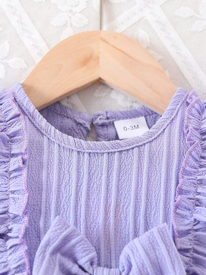 Baby girl wearing a purple ruffle dress with a bow and matching headband