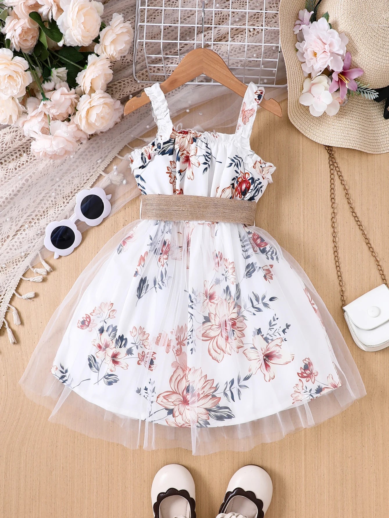 Girl wearing a floral print mesh pinafore dress with a waist belt