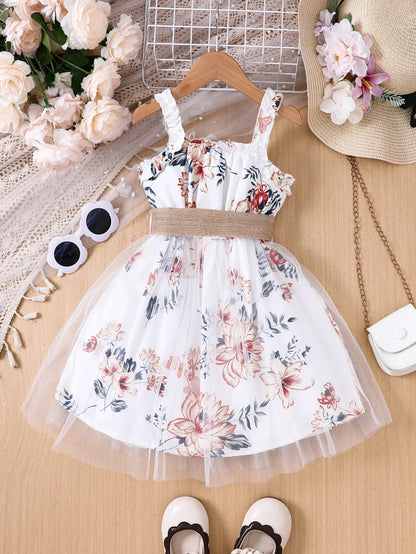 Girl wearing a floral print mesh pinafore dress with a waist belt
