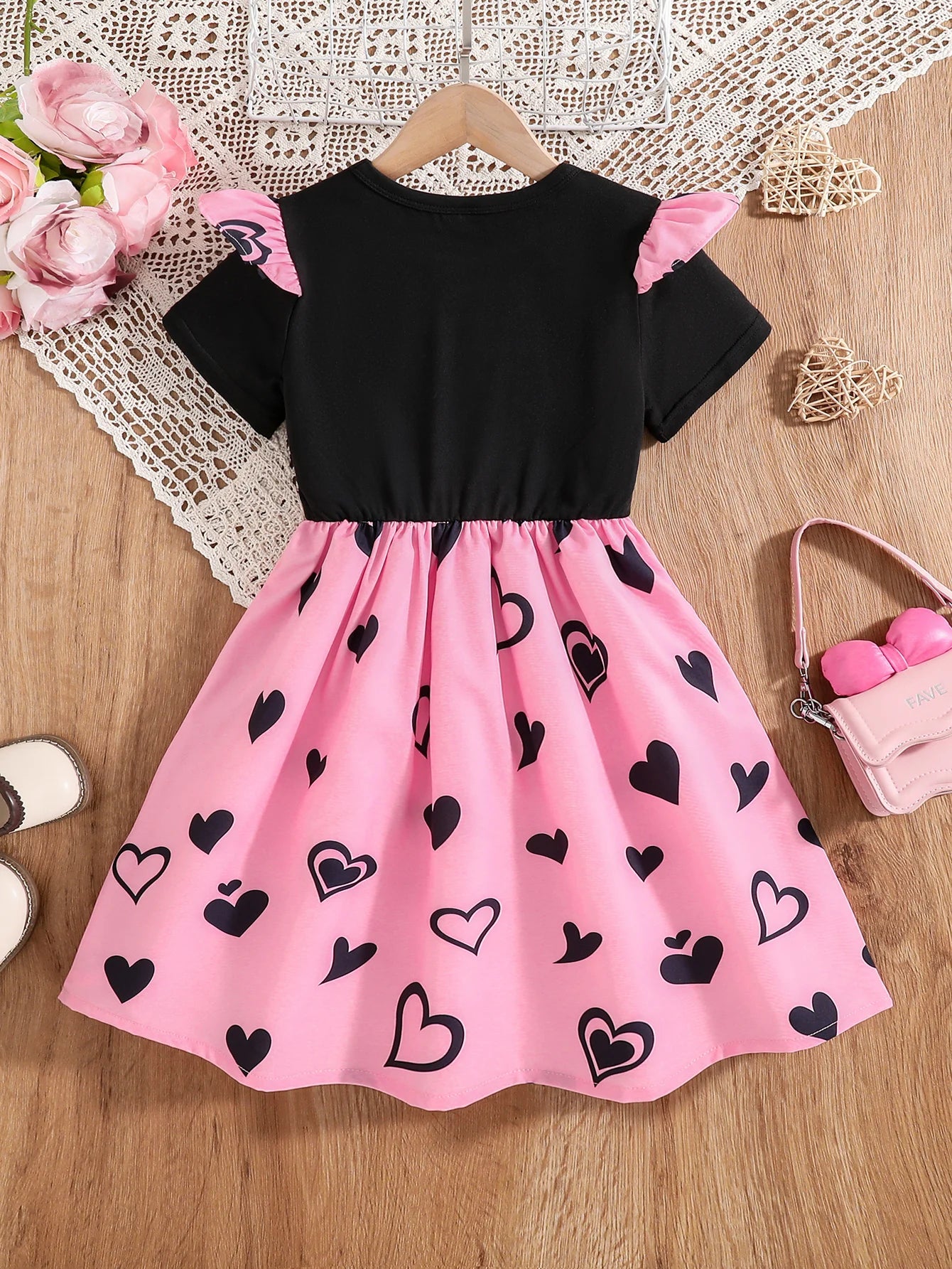 Girl wearing a mid-length dress with a cat and heart print and flutter sleeves