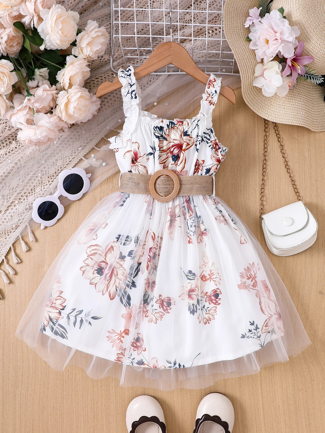 Girl wearing a floral print mesh pinafore dress with a waist belt
