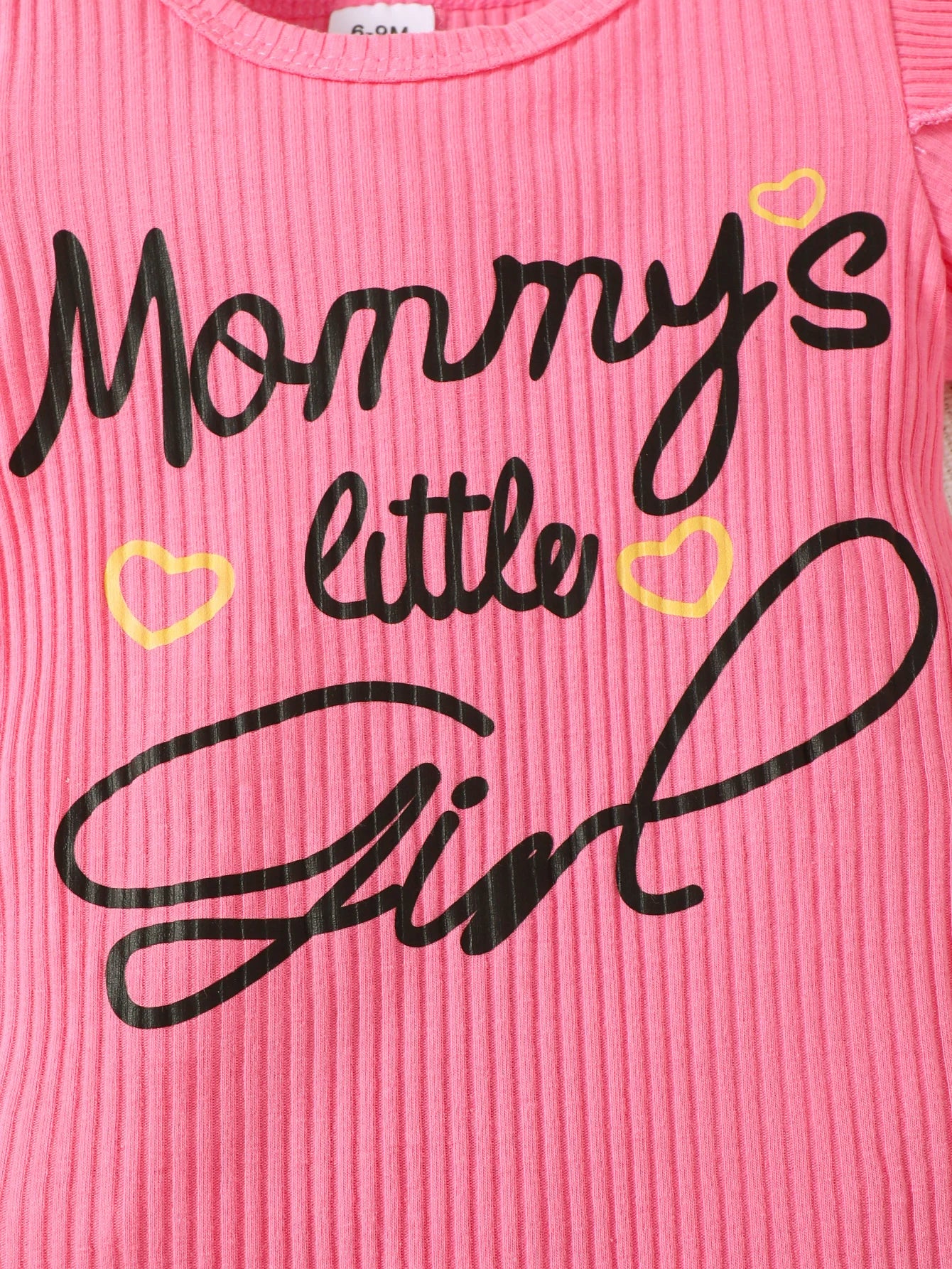 Close up highlighting the hem and stitching on the baby girls letter print romper and denim skirt set