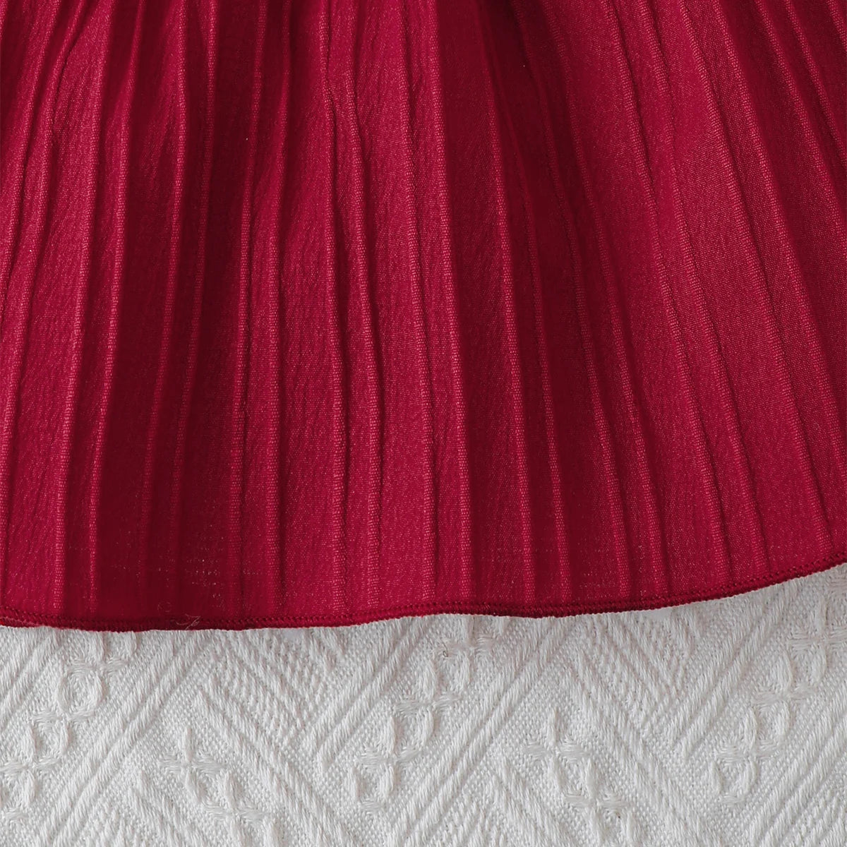 Baby girl wearing a solid colour sleeveless dress with ruffled edges and a headband