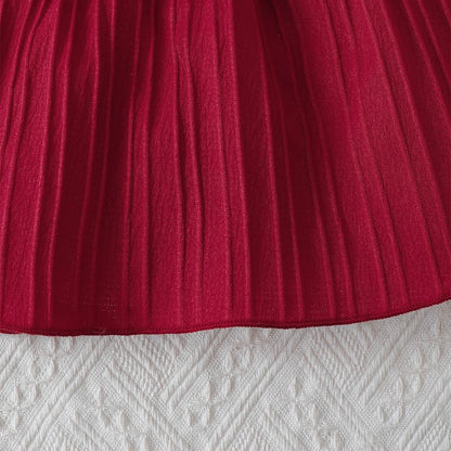 Baby girl wearing a solid colour sleeveless dress with ruffled edges and a headband
