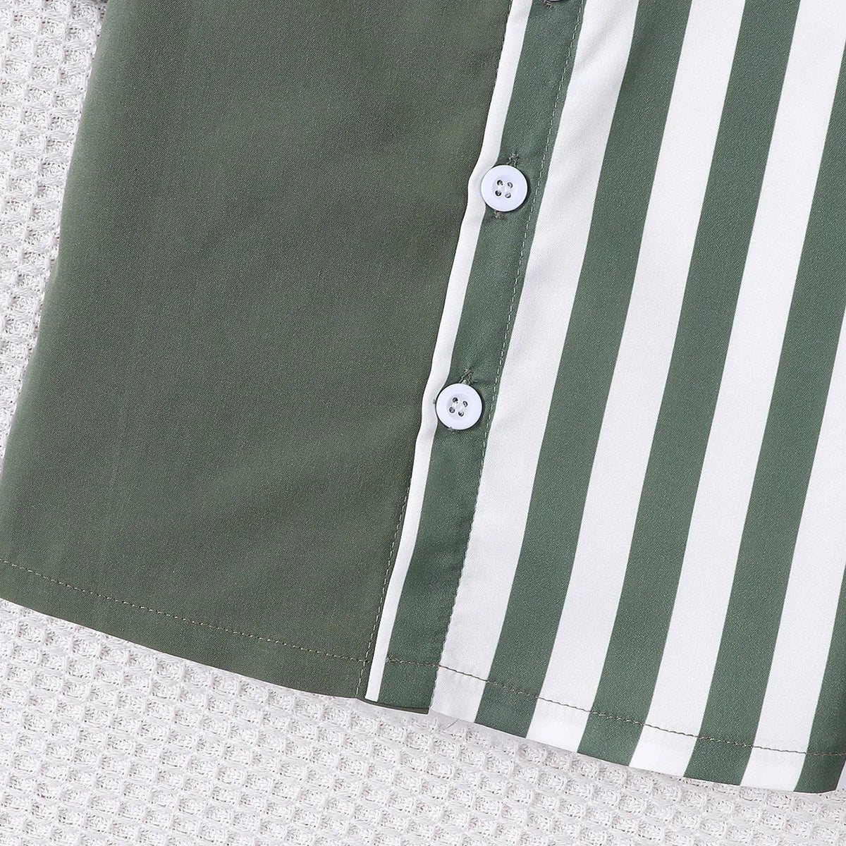 Close up highlighting the hem and stitching on the baby boys colour block short sleeve shirt and shorts set