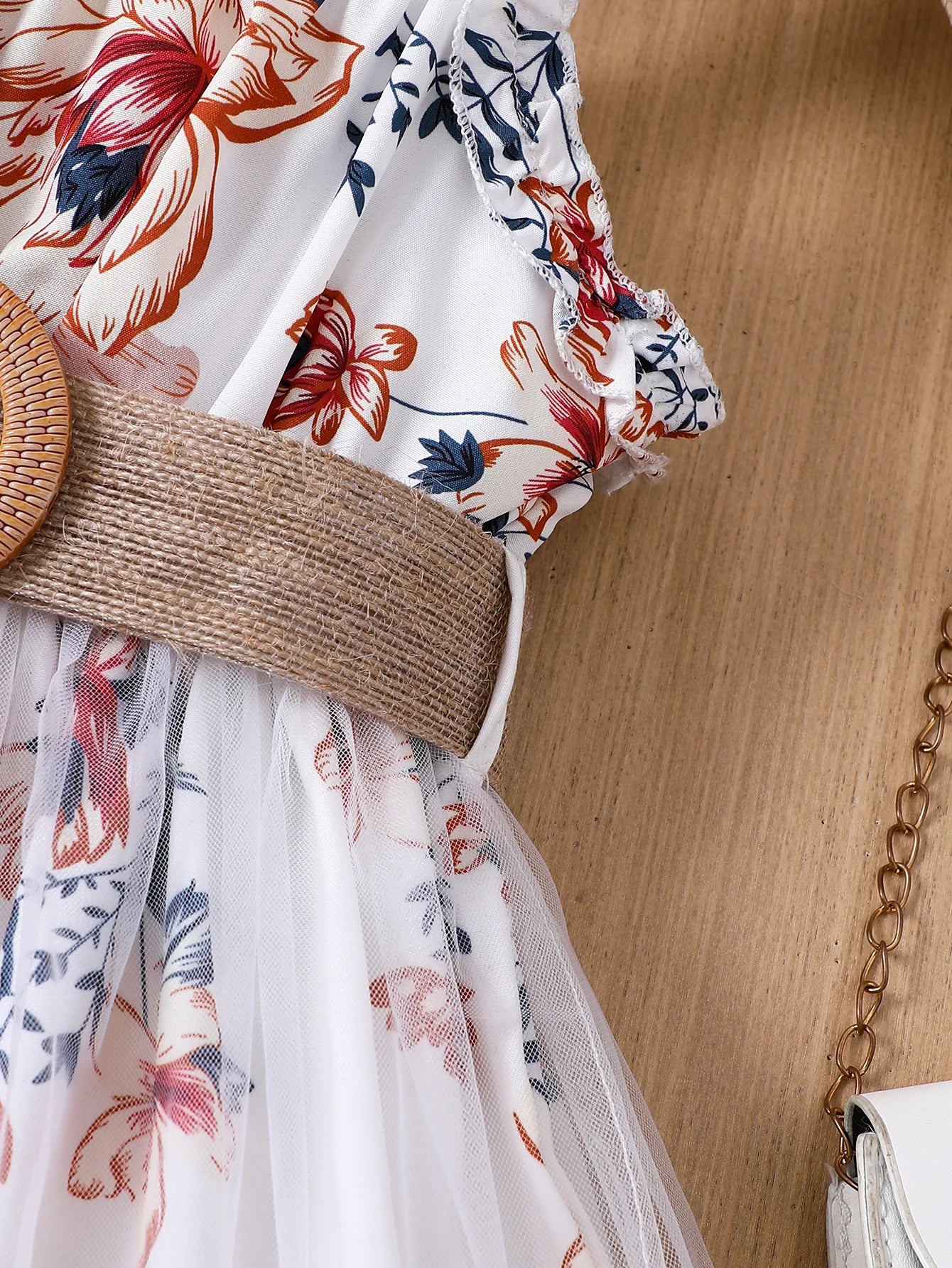 Girl wearing a floral print mesh pinafore dress with a waist belt