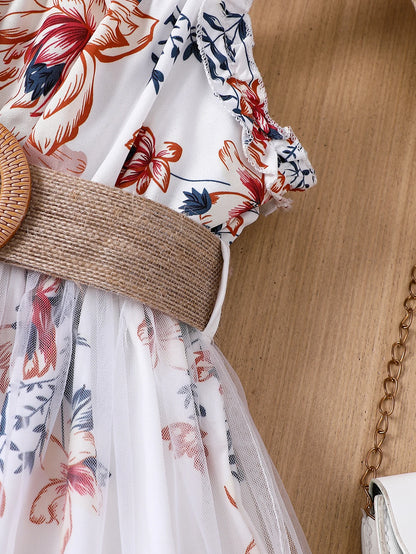 Girl wearing a floral print mesh pinafore dress with a waist belt