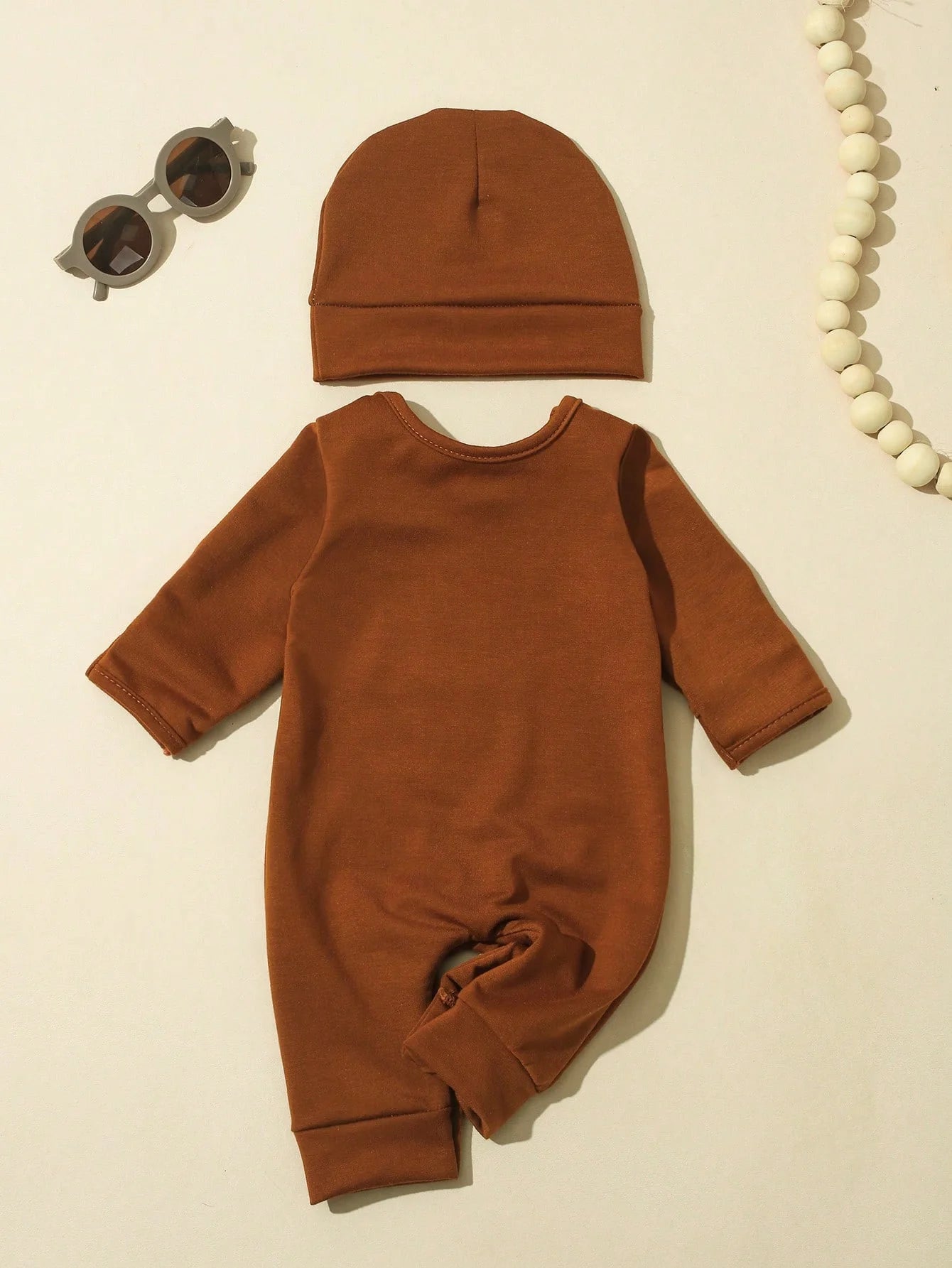 Close-up material detail of newborn boys letter print button bodysuit and hat