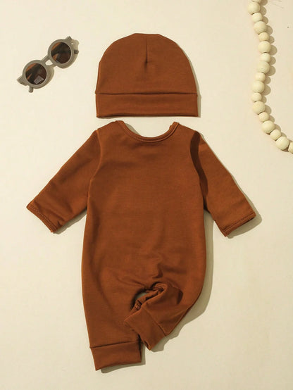 Close-up material detail of newborn boys letter print button bodysuit and hat
