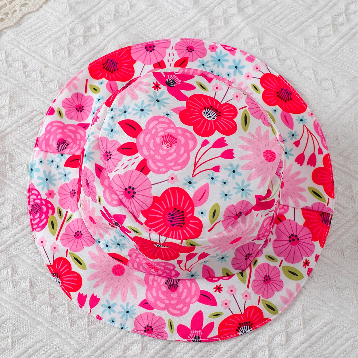 Baby girl wearing a sleeveless floral dress with a bow and matching sun hat